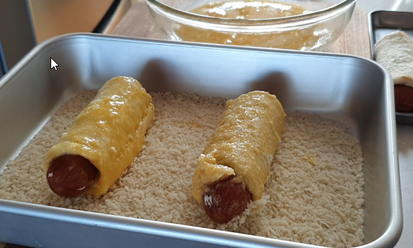 Coating bread roll with egg and breadcrumbs for Korean corn dogs